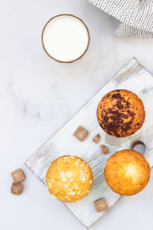 Vanilla muffins and muffins with streusel in paper cups with a glass of milk on light background. Breakfast or snack for children.の写真素材