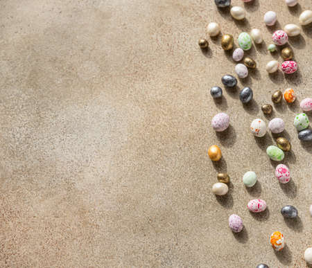 Multicolored candies shaped eggs on a light concrete background. Happy Easter holiday. Minimalism...