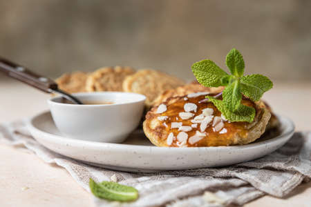 Healthy oat pancakes with jam, nuts and mint on ceramic plate. Vegan breakfast food. Selective...