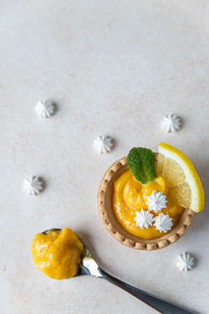Shortbread mini tart with lemon curd, mint and lemon slices and mini meringue, light concrete background. Top view. Copy space. Selective focus.の写真素材