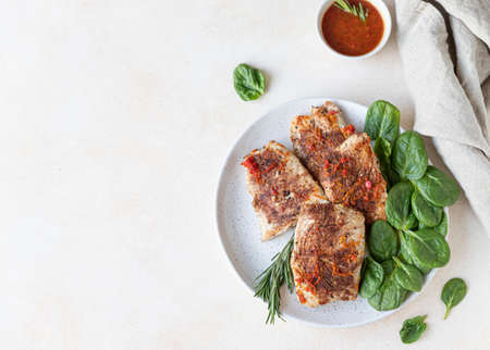 Fried turkey or chicken breast served with orange sauce, spinach and rosemary on a plate, light...