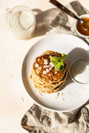 Healthy oat pancakes with jam, nuts and mint on ceramic plate. Vegan breakfast food. Selective...