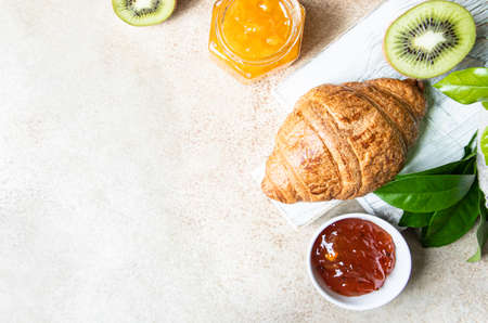French croissant with jam and kiwi on light background. Tasty croissant. Copy space. Top view.の写真素材