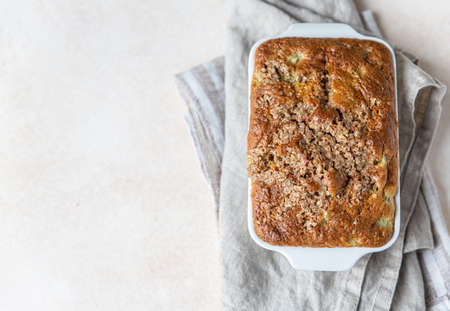 White ceramic baking dish with healthy vegan crumble cake, light concrete background. Healthy...