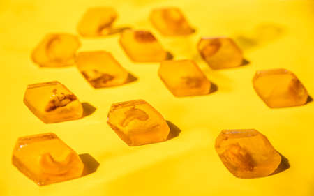 Yellow honey marmalade candy with nuts, yellow background. Marmalade without sugar. Healthy dessert.の写真素材