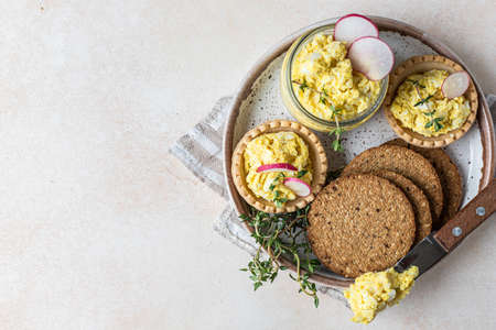 Plate with tartlets, multigrain crackers with egg pate or salad served with radish and thyme. Top view.の写真素材