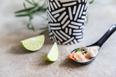 Traditional Asian soup Tom yum kung in a disposable cup of craft paper. Soup to go, food delivery. Take away food. Close up.の写真素材