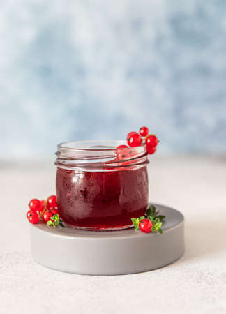 Glass jar with red currant jelly or jam and fresh red currant berries. Selective focus.の写真素材
