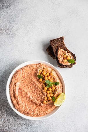 Roasted red pepper hummus garnish with mint and lime. Mashed chickpeas with red bell pepper, lime and mint. Vegetarian snack. Selective focus. Top view.の写真素材