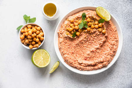 Roasted red pepper hummus garnish with mint and lime. Mashed chickpeas with red bell pepper, lime and mint. Vegetarian snack. Selective focus. Top view.の写真素材