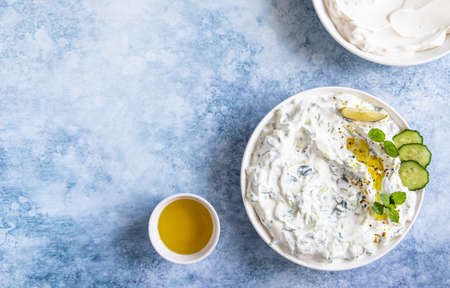 Indian or Pakistani raita sauce or dip with cucumber, yoghurt, garlic and mint, blue concrete background. Traditional Indian cuisine. Selective focus. Top view.の写真素材