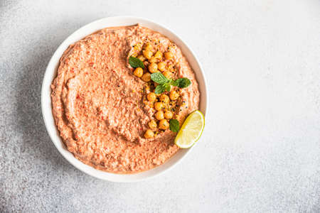 Roasted red pepper hummus garnish with mint and lime. Mashed chickpeas with red bell pepper, lime and mint. Vegetarian snack. Selective focus. Top view.の写真素材