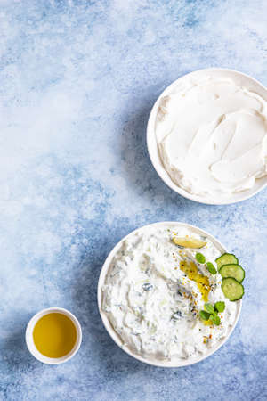 Indian or Pakistani raita sauce or dip with cucumber, yoghurt, garlic and mint, blue concrete background. Traditional Indian cuisine. Selective focus. Top view.の写真素材