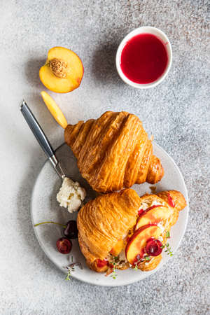 Croissant with nectarine, cherry and ricotta cheese, gray stone background. Tasty breakfast. Top view. Selective focus.の写真素材
