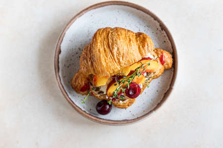 Croissant sandwich with cream cheese, nectarine and cherry. Selective focus.の写真素材