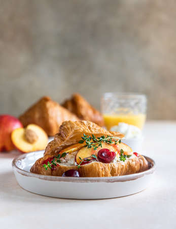 Croissant sandwich with cream cheese, nectarine and cherry and fresh ingredient for making tasty breakfast.の写真素材