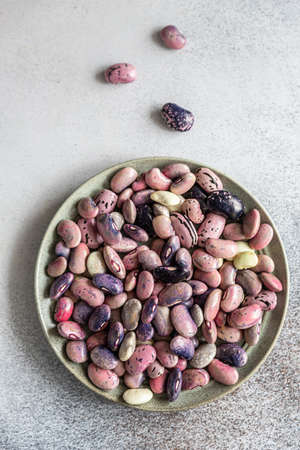 Colorful legumes on ceramic plate, concrete background. Substitution of meat, high protein product. Top view. Selective focus.の写真素材