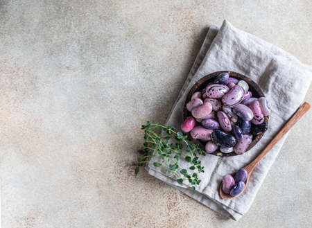 Ceramic bowl with colorful legumes and thyme, concrete background. Vegan high protein product. Top view. Selective focus. Copy space.の写真素材