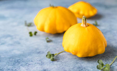 Fresh ripe yellow patissons, squash or dish-shaped pumpkin on blue concrete background. Harvest of...