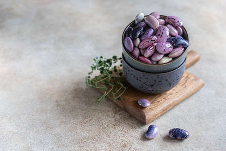 Ceramic bowl with colorful legumes and thyme, concrete background. Vegan high protein product. Selective focus.の写真素材