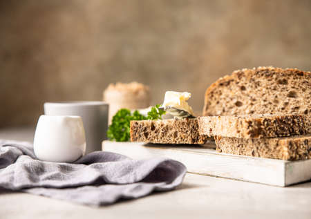 Freshly baked artisan multigrain bread with butter and pate. Breakfast with coffee, sliced bread, butter and liver pate. Light gray stone background.の写真素材