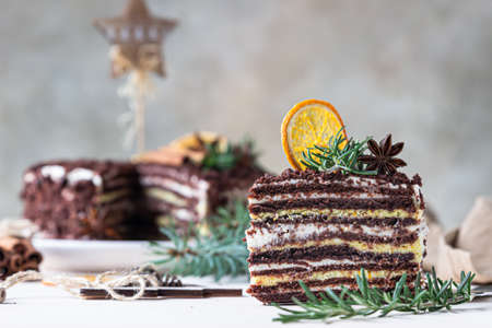 Chocolate layered cake decorated with rosemary, spices and dried orange slices. Festive Christmas or New Year decor. Russian honey cake, Medovik. Selective focus.の写真素材