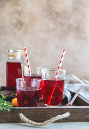 Roselle or karkade tea in glass with dried tea leaves on wooden tray. Red tea. Healthy herbal drink...