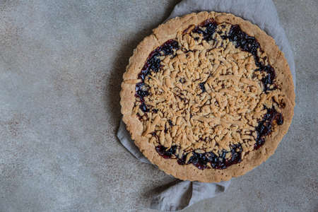 Homemade tasty shortcrust jam pie with crumble on concrete background. Top view.