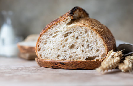 Loaf of freshly baked sourdough bread on cutting board with milk. Artisan rustic sourdough bread....
