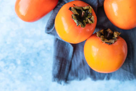 Fresh organic ripe persimmons on blue concrete background.の写真素材