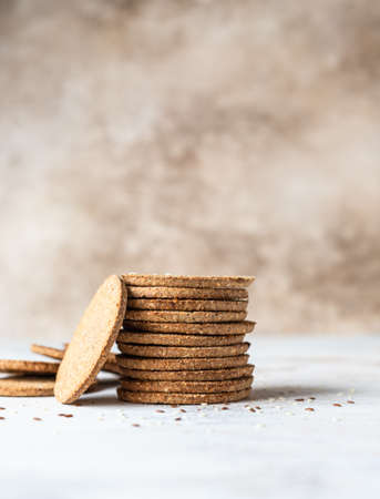 Stack of tasty crackers with sesame and flax seeds on gray background. Healthy snack. Selective focus.の写真素材