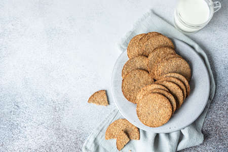 Plate with tasty crackers and a cup of milk. Snack or breakfast on gray stone background. Top view....
