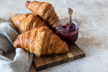 Fresh crispy croissants with jam, concrete background. Homemade bakery for tasty breakfast.