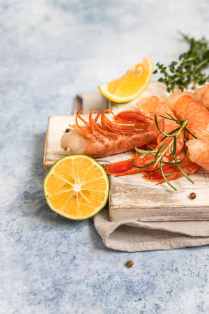 Raw Argentine shrimps on white wooden cutting board with lime, herbs and pepper. Seafood.の写真素材