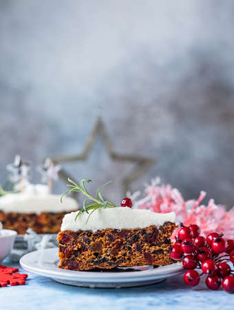 Christmas fruit cake or pudding decorated with glaze, rosemary and cranberries, blue background. Traditional winter bakery. Festive Christmas or New Year background.の写真素材
