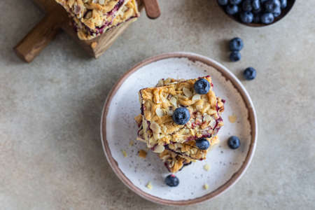 Crumble cheesecake bars with blueberry filling and fresh blueberries, concrete background. Bar slices with cheesecake, blueberry and streusel. Top view.の写真素材