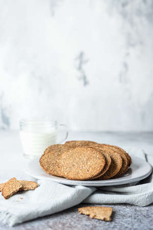 Plate with tasty crackers and a cup of milk. Snack or breakfast on gray stone background. Selective...