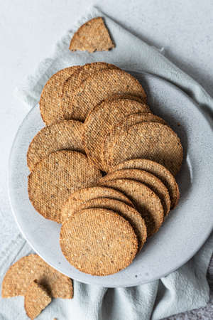Plate with tasty crackers with sesame and flax seeds on gray stone background. Top view. Selective...