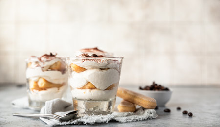 Traditional Italian dessert tiramisu in glass. Coffee flavored portion dessert made of savoiardi and mascarpone decorated with cocoa powder.の写真素材