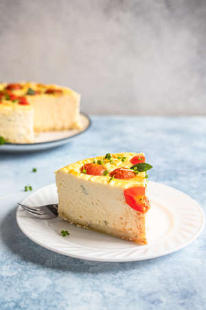 Piece of savoury tomato cheesecake with herbs decorated mint, blue background.