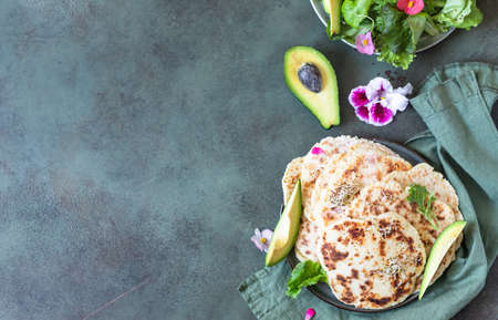 Homemade chapati or roti flatbread with green salad mix, avocado and sprouts on concrete background. Freshly baked Indian flatbread. top view.の写真素材