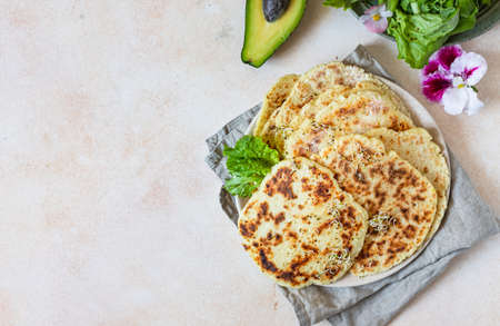 Homemade chapati or roti flatbread with green salad mix, avocado and sprouts on concrete background....