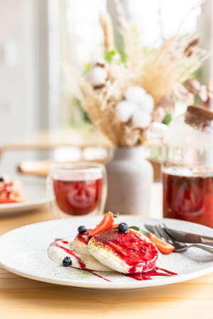 Breakfast in cafe with cottage cheese pancakes with sour cream and red berry sauce and fresh...