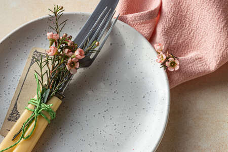 Romantic, wedding or spring table setting. Empty plate with card and pink flowers, light concrete...