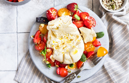 Salad with burrata cheese, cherry tomatoes and strawberry with micro green and olive oil. Traditional Italian burrata cheese. summer food. Healthy eating concept. Keto diet.の写真素材