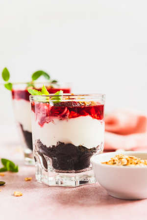 Cherry, cream cheese and chocolate biscuit portion layered dessert in glass, pink background. Black forest trifle. No bake summer dessert.の写真素材