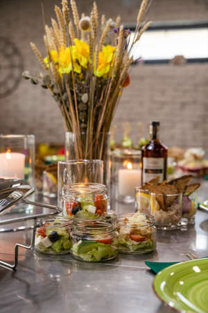 Banquet table served for holiday with canape and snacks, wine glasses, candles and flowers. European...