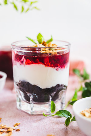 Cherry, cream cheese and chocolate biscuit portion layered dessert in glass, pink background. Black forest trifle. No bake dessert.の写真素材