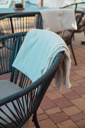 Outdoor terrace of a restaurant or cafe. Blankets hang on the backs of the chairs. Background with a view of the yacht club.の写真素材