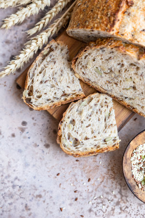 Sliced loaf of artisan sourdough bread with multigrain seeds. Tartine with honey and seeds, concrete...